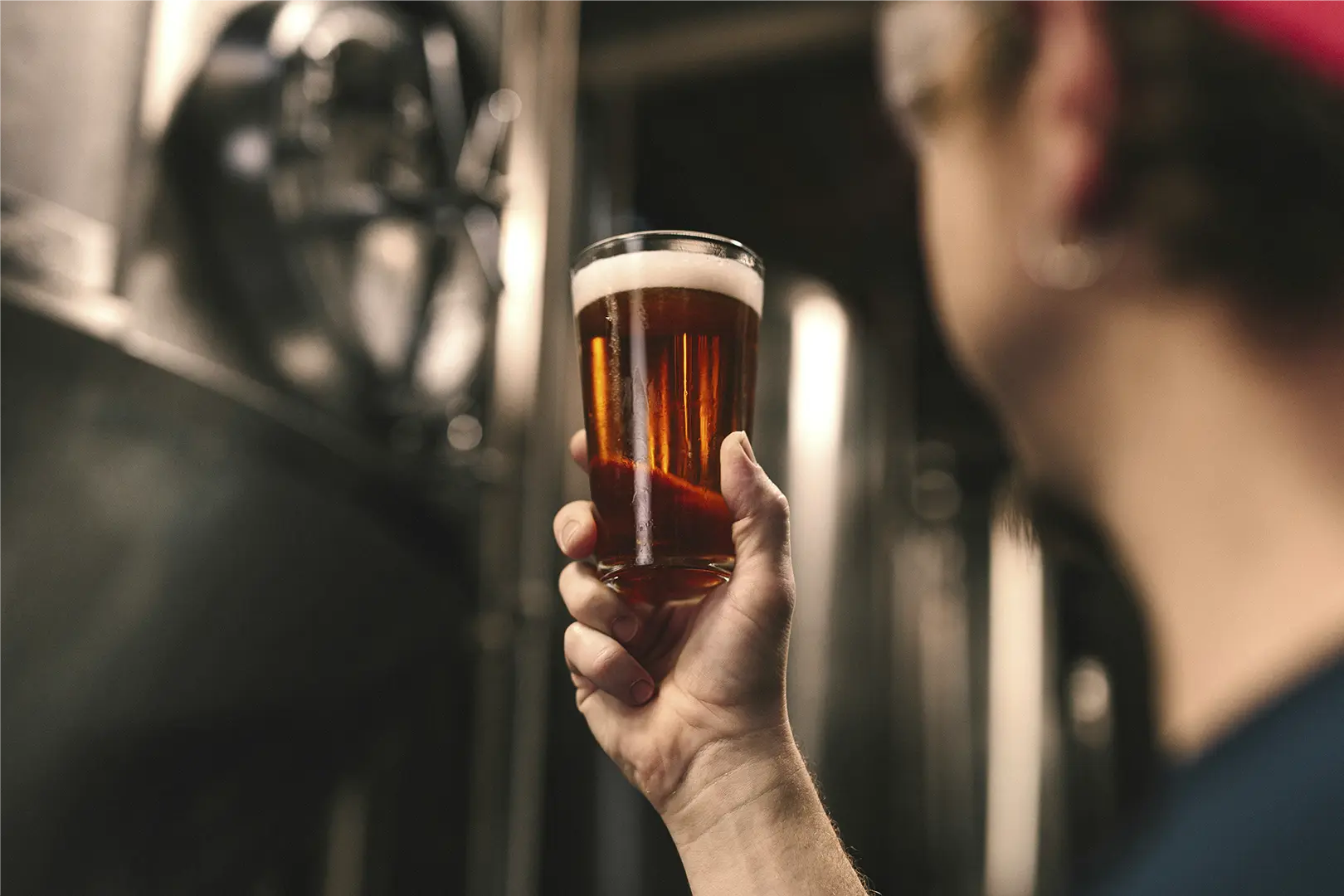En øl i et glas der holdes op i luften